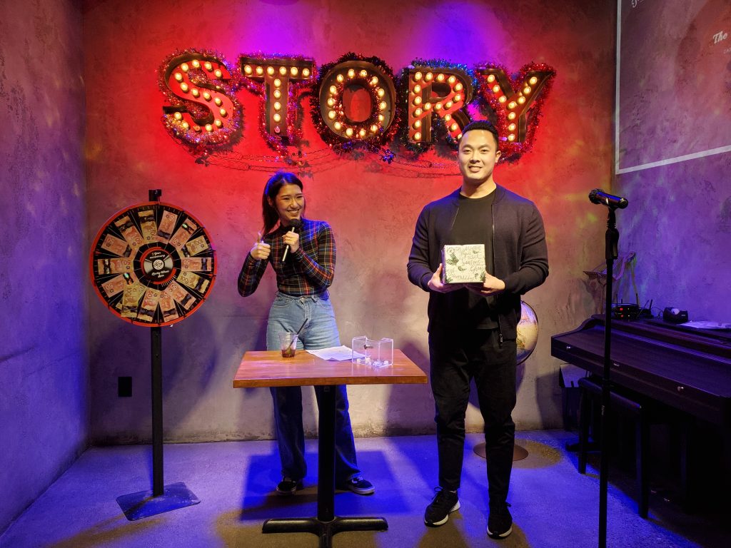 A lucky-draw winner on stage under the STORY sign