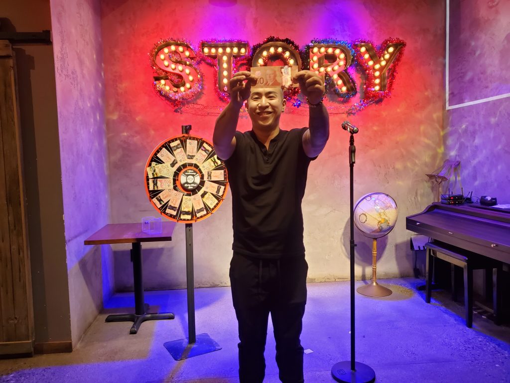 A lucky-wheel winner holding up a $50 prize