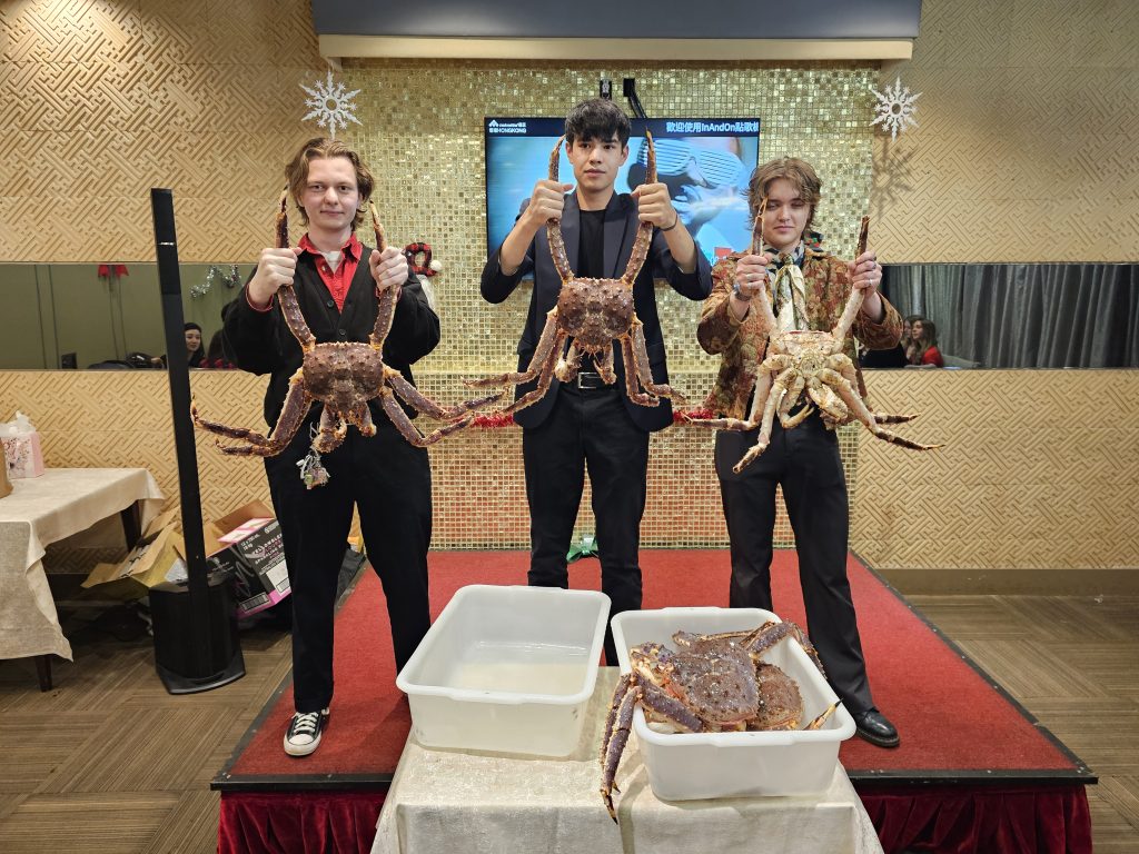 Three team members holding up king crabs on stage